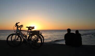 Deux personnes assises sur le sable avec leurs vélos