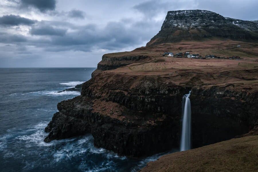 Falaises en bord de mer et petit village à découvrir lors d'un autotour en Islande