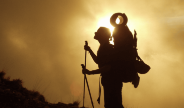 Visite Oman : un randonneur sous un coucher de soleil dans le désert omanais avec une vue sur le paysage