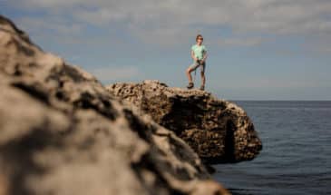 Randonneur accompagner: Fille sur le rocher avec des bâtons de marche sur le beau fond de la mer et ciel clair à Chypre