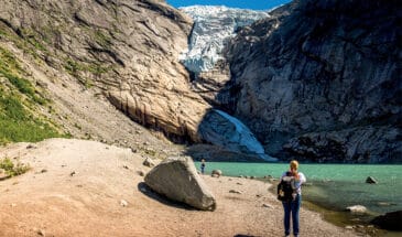 Touristes face à une falaise à coté d'un lac