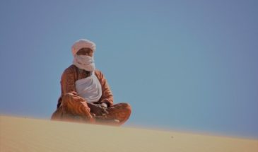 Un touareg assis sur le sable dans le désert Tassili dans le Nord à Hoggar en Algérie