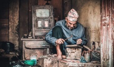 Artisanat Népal : un homme est assis dans un atelier. Il fabrique des objets de ses mains.