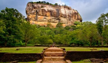 Dambulla montagnes Sri Lanka : il y a une grande montagne, entourée d'arbres sous lesquels sont les touristes.