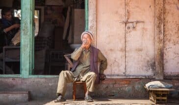 Habitant Népal : il y a deux hommes, l'un est assis sur un tabouret et fume et l'autre est un barbier.