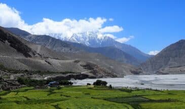 Mustang Népal : il y a des champs, une caravane et au loin, il y a des montagnes.