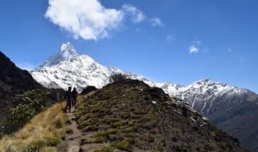 Randonneurs vers montagne Népal : il y a deux personnes en excursion. Au loin, il y a des monts enneigés.