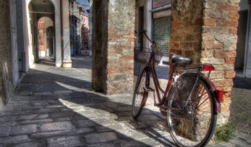 Vélo rouge contre un mur dans une rue de Trevise