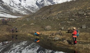 Des randonneurs dans le camp de base de l'Annapurna, près des montagnes enneigées et d'un lac.