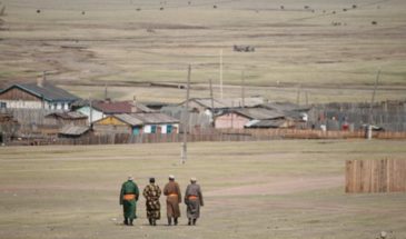 Mongolie trek : 4 hommes seniors se baladant en Mongolie, en face des villages et des maisons.