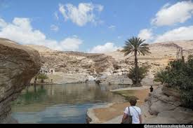 Le Moyen Orient Oman, des visiteurs autour d'un lac d'Oman et avec de grands rochers admirant la vue.