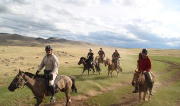 Randonnée en Mongolie : il y a des touristes à cheval dans un paysage désertique au large des collines.