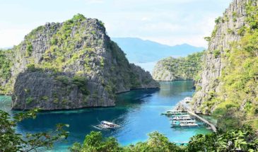 Rochers coron Philippines : il y a des bateaux sur l'eau qui naviguent entre les grands rochers entourés de verdures.