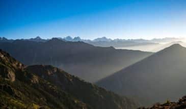 Trek Langtang : il y a une vallée avec de la végétation et on trouve au loin des montagnes.