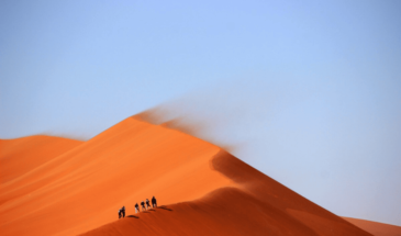 Randonnée dans le désert d'Oman aux couleurs orangées sous un magnifique ciel bleu