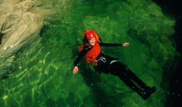 Touriste en randonnée aquatique se baignant dans une eau verte.