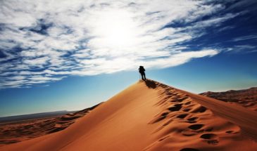 Touriste en randonnée dans le désert tunisien au sommet d'une dune.