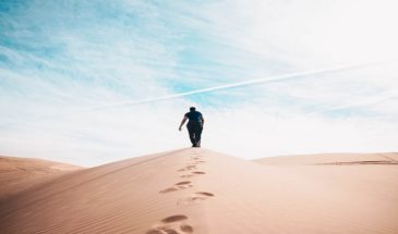 Touriste en randonnée pédestre sur une dune du désert.