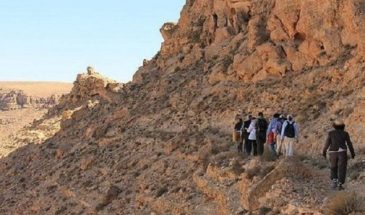 Touristes en randonnée sur une colline rocheuse du désert en Tunisie.