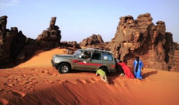Des touristes poussant une voiture 4x4 dans le désert Tassili Hoggar dans le Nord de l'Algérie