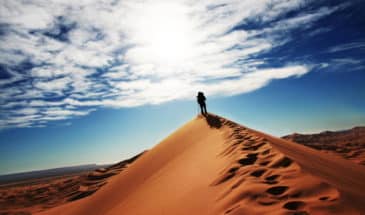 Touriste en trekking sur le sommet d'une dune au Maroc.