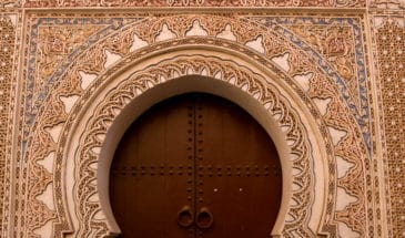 Porte d'une maison marocaine décorée tout autour de motifs orientaux.