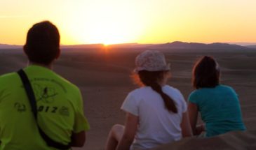 Famille de touristes assis dans le désert, regardant à l'horizon.