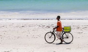 Cycliste traînant son vélo à pied sur une plage mauritanienne.