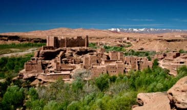 Vieilles maisons en pierre dans un village marocain entouré de végétation.