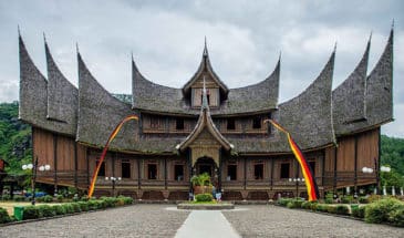 Compilation Sumatra : une structure grise et marronne en forme de pic sur le toit avec un jardin.