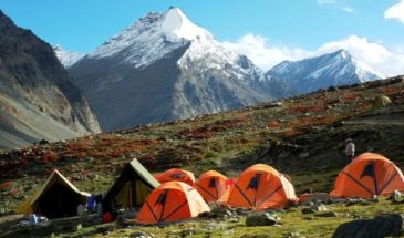 Des tentes dans les montagnes enneigées de l'Inde ainsi que des randonneurs combinés d'un ciel bleu.