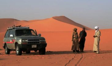 Touriste en visite du circuit Djanet d'Algérie dans une voiture en 4x4 sur le sable rouge
