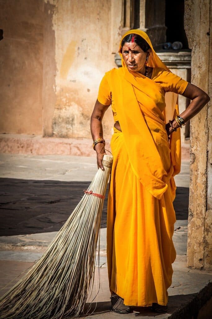 Inde séjour trekking : une femme senior indienne, habillée en robe jaune et ayant un ballait traditionnel.
