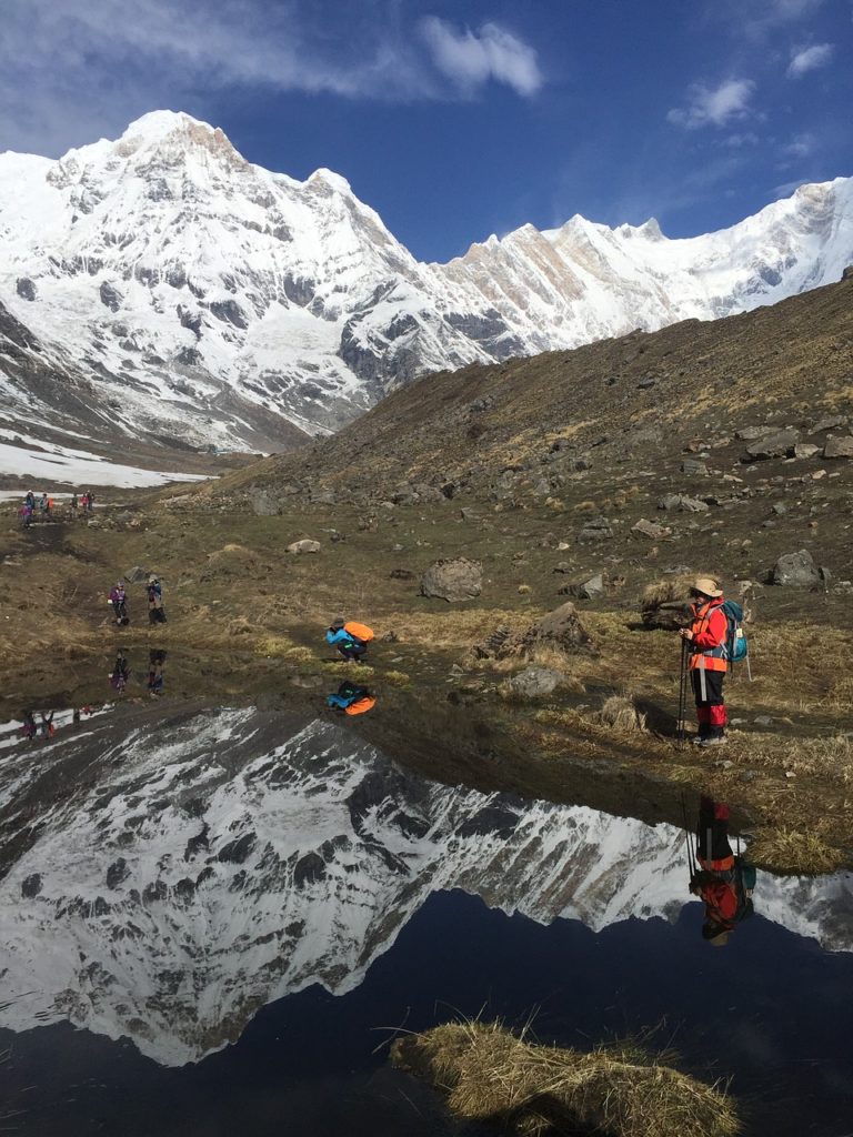 Randonnée Annapurna : il y a des personnes à côté d'un lac, en excursion dans les montagnes.