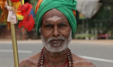 Séjour au Sri Lanka, un homme vêtu d'un accoutrement traditionnel, un foulard, des colliers et qui tient un bâton.