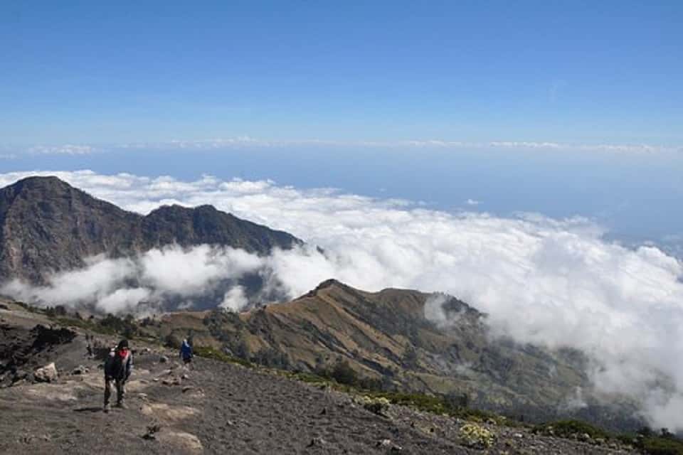 Trek Bali : des randonneurs au sommet d'une montagne, pour explorer un paysage densifié par un nuage.