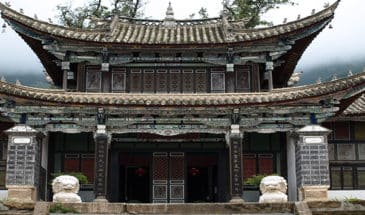 Trek Yunnan : un temple typiquement chinois, de couleur sombre, avec deux statues de têtes à l'entrée.