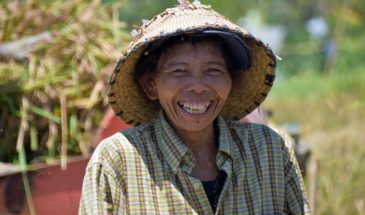 Visite Bali : il y a une femme paysanne qui porte un chapeau de paille et qui sourit.
