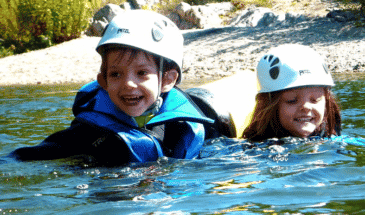 Une petite fille et un petit garçon en train de nage dans le lacs avec un magnifique sourire, canyoning Cevenne