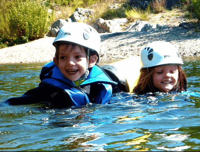 Une petite fille et un petit garçon en train de nage dans le lacs avec un magnifique sourire, canyoning Cevenne