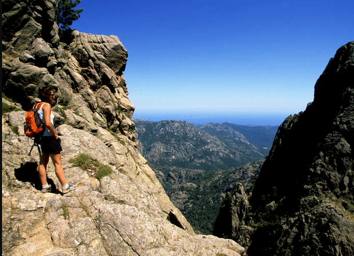 Femme debout sur des montagnes admirant la splendeur du paysage gr20 sud