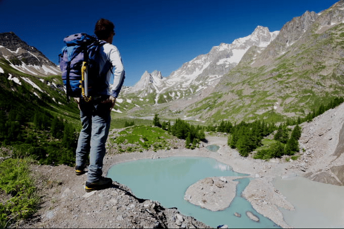 Homme observant le paysage magnifique composé de lac, forêt et montagnes,le grand tour du mont blanc