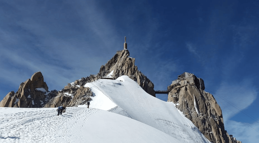 Un groupe marche sur la piste montagneuse plein de neige vers le sommet de la montagne, monter le mont blanc.