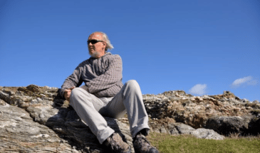 Homme assis sur une roche admirant la splendeur du paysage qui s'offre à lui,randonnée en famille