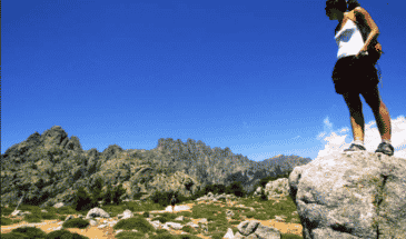 Une femme sur une roche qui admire d'autres montagne,trek Corse