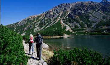 Un couple qui passe à cote d’un lac sur leur chemin pour atteindre le sommet de la montagne trekking Roumanie