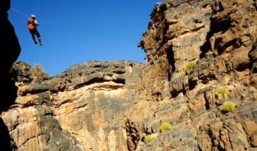 Kayak Oman : un homme faisant de la tyrolienne dans un grand canyon d'Oman