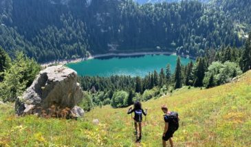 Rando suisse couple marchant en direction du lac bleu vue sur un rocher et les arbres du Val d’Hérens